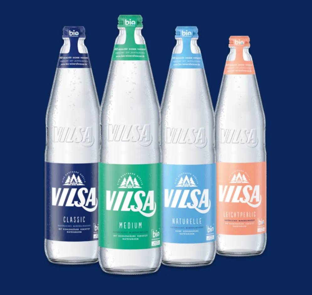 Vier Glasflaschen von VILSA Bio-Mineralwasser stehen nebeneinander. Die linke Flasche ist VILSA Classic mit Kohlensäure, die mittlere ist VILSA Medium mit weniger Kohlensäure, die rechte ist VILSA Naturelle ohne Kohlensäure und die letzte Flasche ist VILSA Leichtperlig.