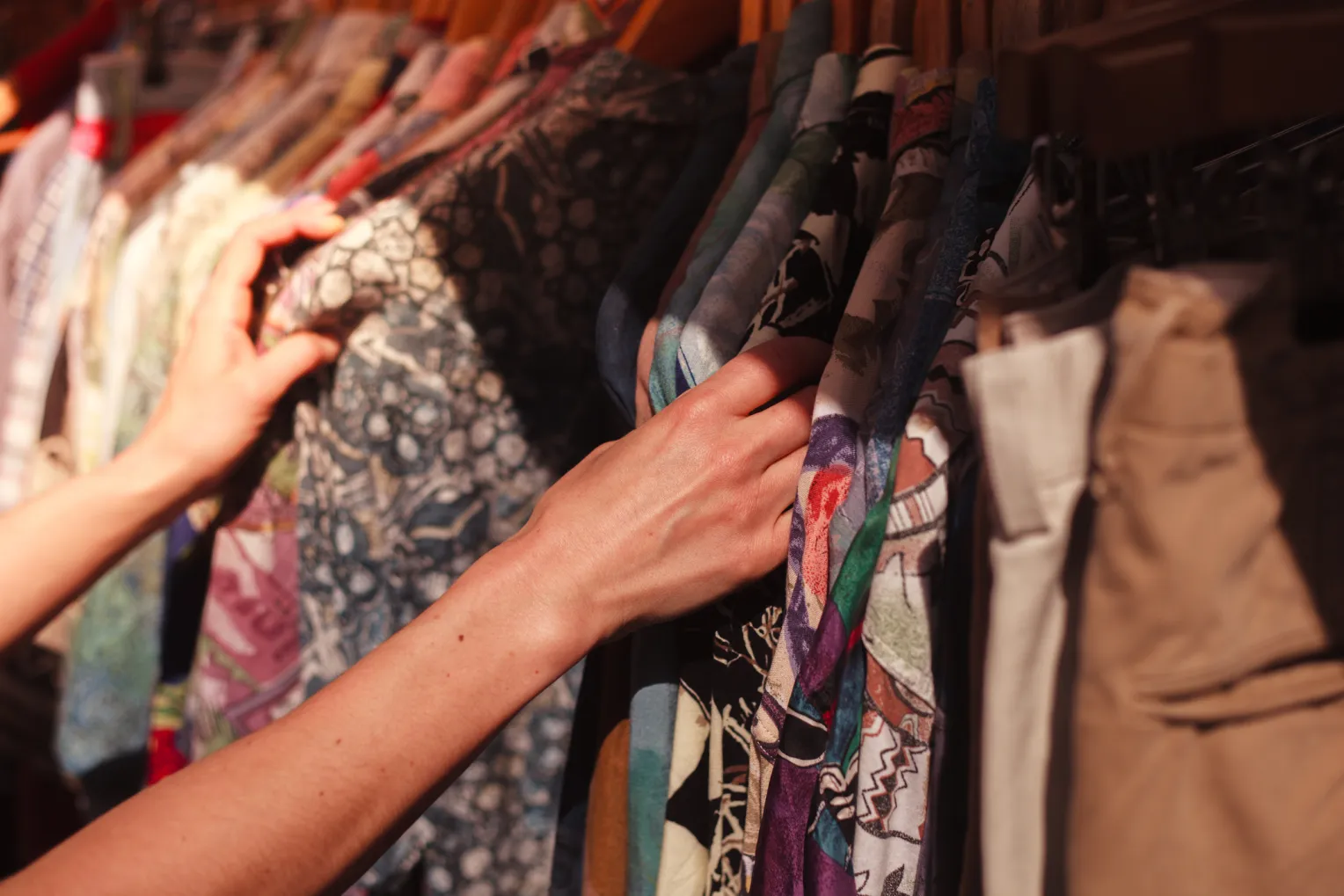 Eine Frau stöbert an einer Kleiderstange in einem Secondhand Geschäft.