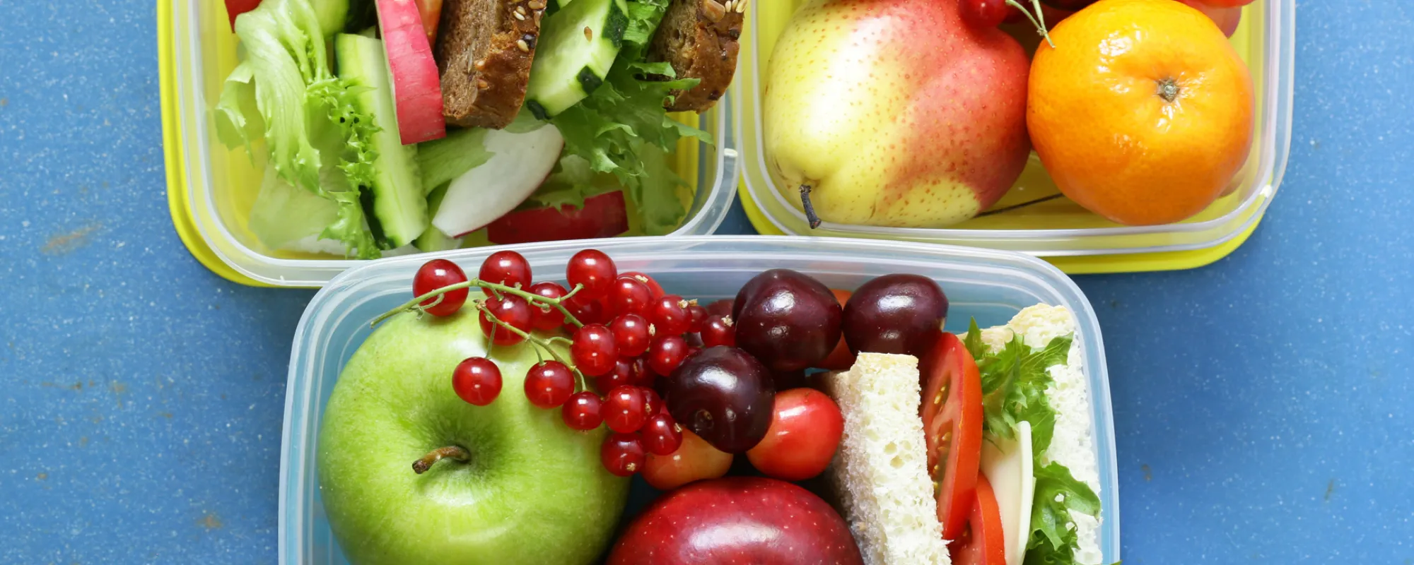 Drei Lunchboxen mit gesundem Essen, Gemüse, Obst und Broten.