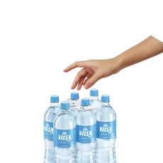 Eine Hand greift nach einem Sixpack VILSA Naturelle Wasserflaschen, das ohne Schrumpffolie auskommt. Die Flaschen sind mit einem Tragegriff aus Pappe verbunden. Der Hintergrund ist freigestellt (schwarz). Die Szene zeigt die einfache Handhabung des nachhaltigen NIX-PACKs.