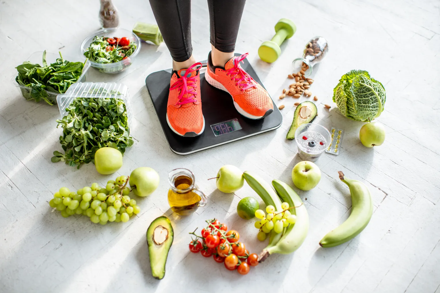 Eine Person in Sportkleidung steht auf einer digitalen Waage, umgeben von gesunden Lebensmitteln wie grünem Gemüse, Obst, Nüssen und Olivenöl. Die Szene vermittelt ein Bewusstsein für Ernährung und Fitness.