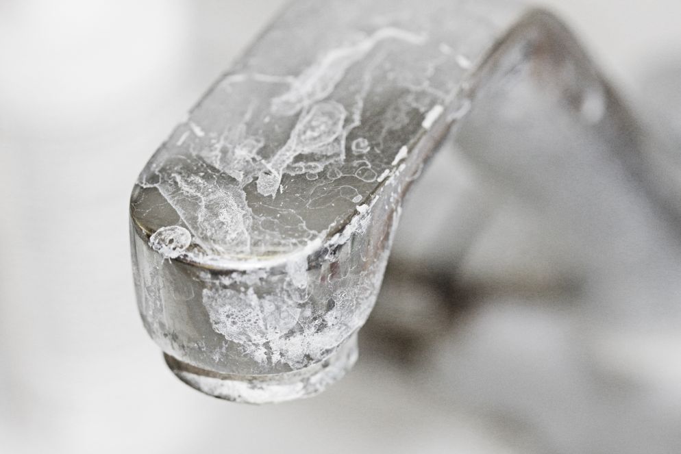 Nahaufnahme eines stark verkalkten Wasserhahns mit sichtbaren weißen Ablagerungen.