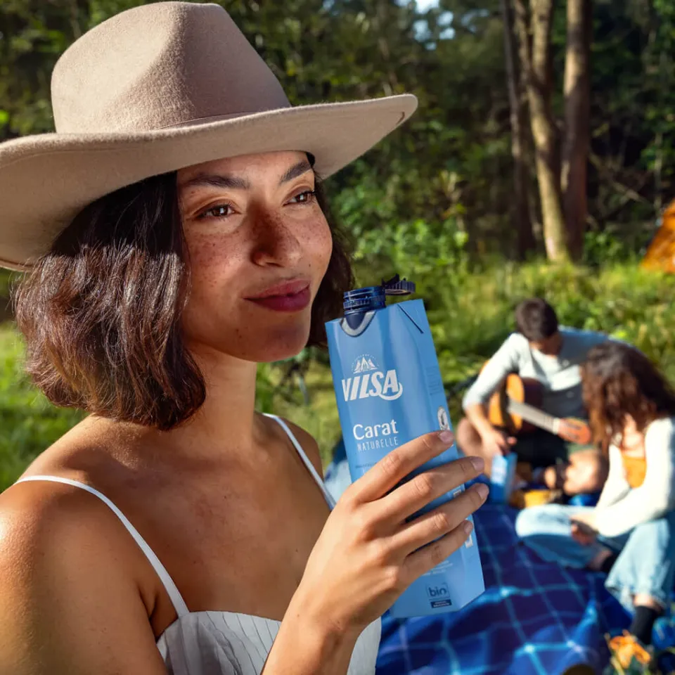 Junge Frau mit hält VILSA Carat Naturelle im Tetra Pak in der Hand beim Picknick.