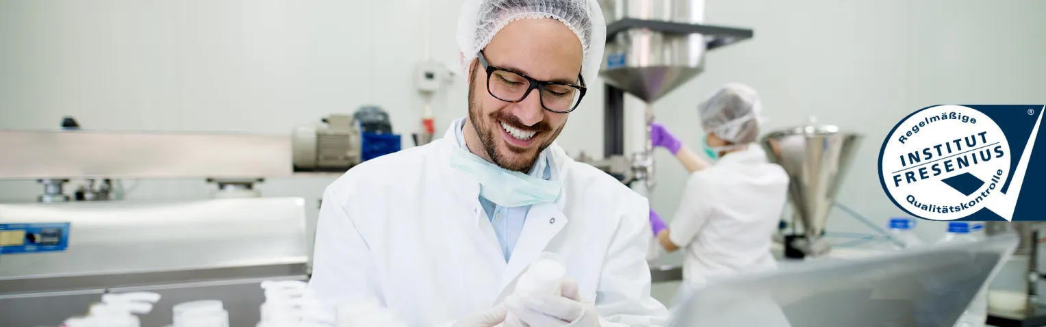 Mann im Laborkittel mit Brille lacht, auf der rechten Bildseite befindet sich das Institut Fresenius Logo