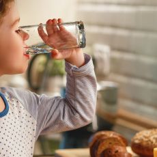 kleines Mädchen trinkt Wasser aus einem Glas in der Küche
