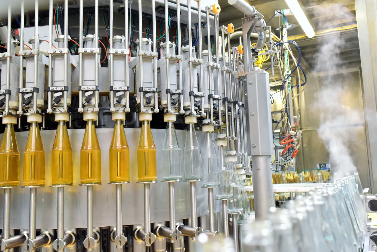 Industrielle Abfüllanlage füllt Getränkeflaschen aus Glas auf einem Förderband.