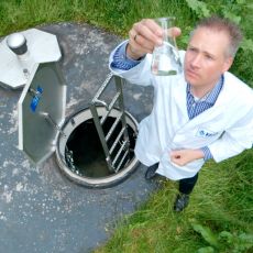 Labormitarbeiter entnimmt Mineralwasserprobe